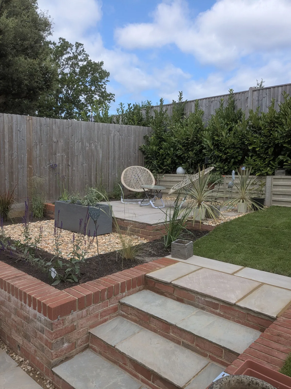 The same corner rebuilt with Indian sandstone steps and a planted gravel bed