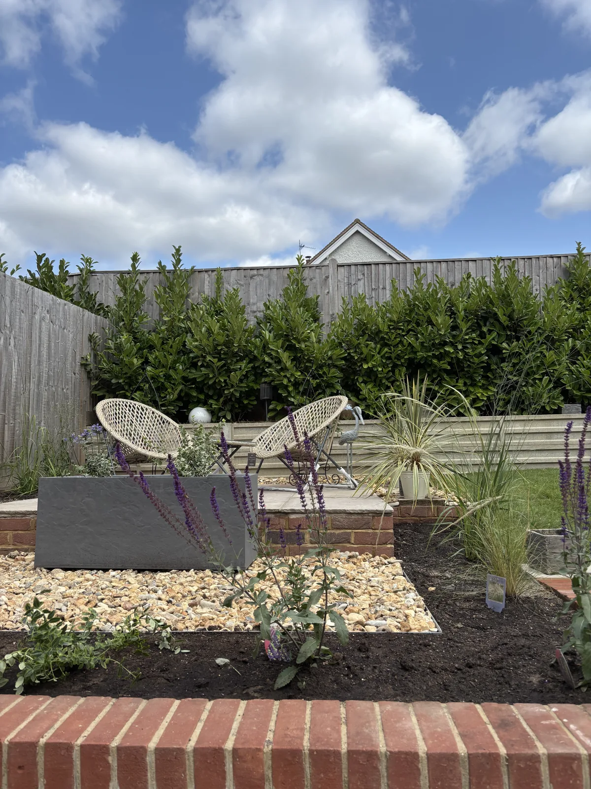 Brick-edged gravel bed with fresh planting, seating and a slate planter